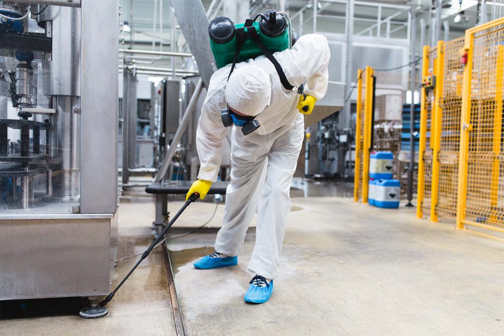 worker spraying below machine
